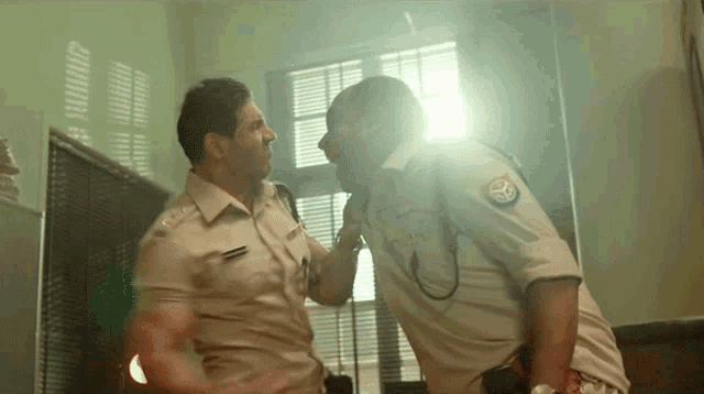 two police officers are fighting in a room and one has a patch on his shirt that says ' rs '