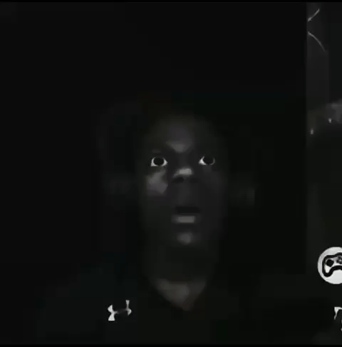 A streamer’s face emerges from darkness with a fearful stare.