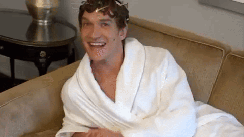 a man wearing a white robe is sitting on a couch and smiling .