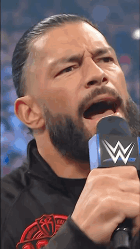 a man with a beard is holding a microphone in his hand .
