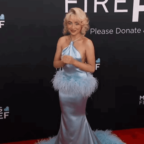 a woman in a blue dress is standing on a red carpet