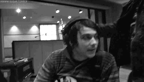 a man wearing headphones is sitting in front of a microphone in a black and white photo .