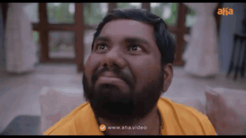 a man with a beard wearing a yellow shirt is looking up at the sky