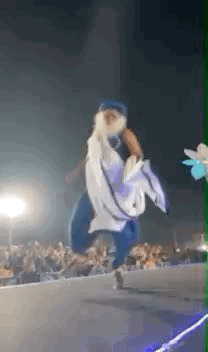 A robed performer dances on a brightly lit outdoor stage.