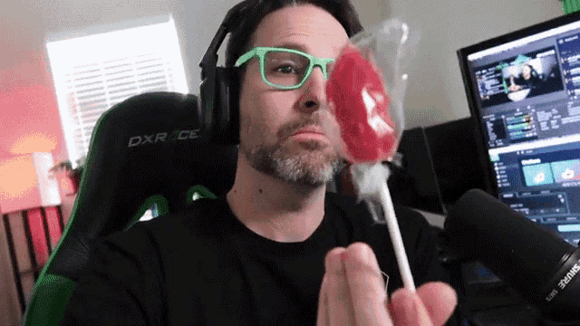 a man wearing glasses and headphones is holding a lollipop in front of a dxr race chair