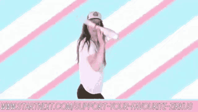 a woman in a white shirt and hat is juggling a ball on a pink and white striped background .
