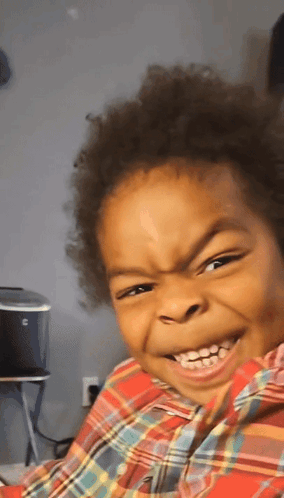 A child makes an exaggerated mischievous grimace-smile.