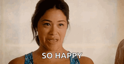 a woman is making a funny face and smiling while saying `` so happy '' .