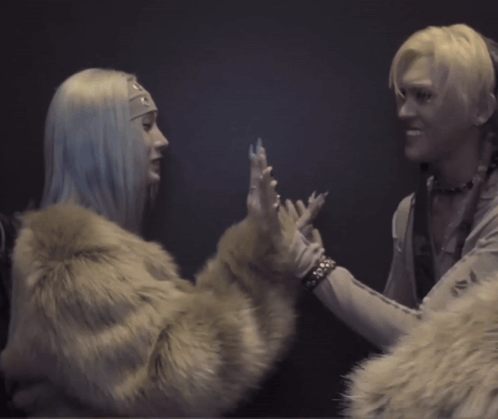 a woman in a fur coat gives a high five to a man in a white shirt