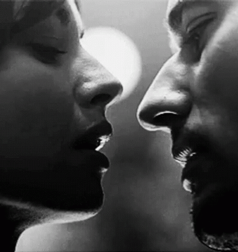 Black-and-white close-up of a couple leaning in for a kiss.