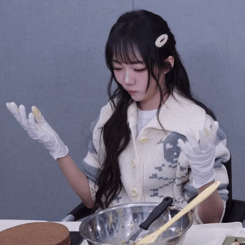 a woman wearing white gloves is sitting at a table