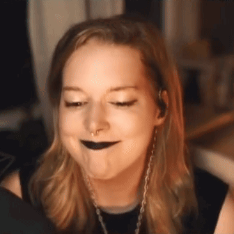 a woman with black lipstick and a nose ring is making a face .