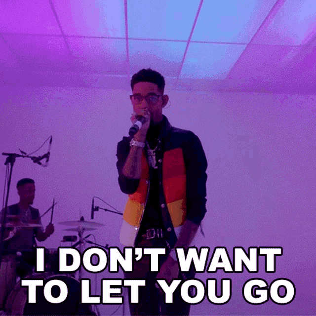 a man singing into a microphone with the words i do n't want to let you go below him