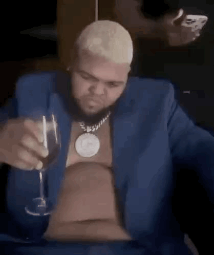 A man in a blue jacket looks down while holding a drink.