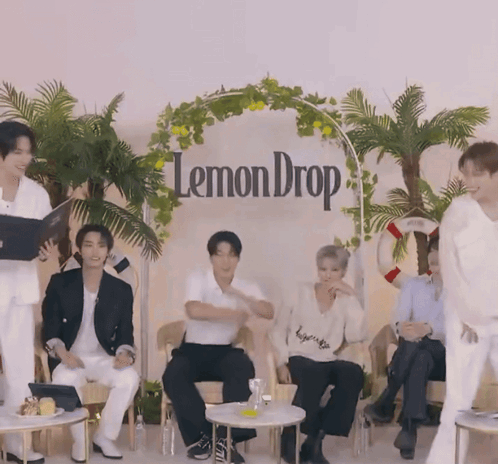 a group of people sit in front of a lemon drop sign