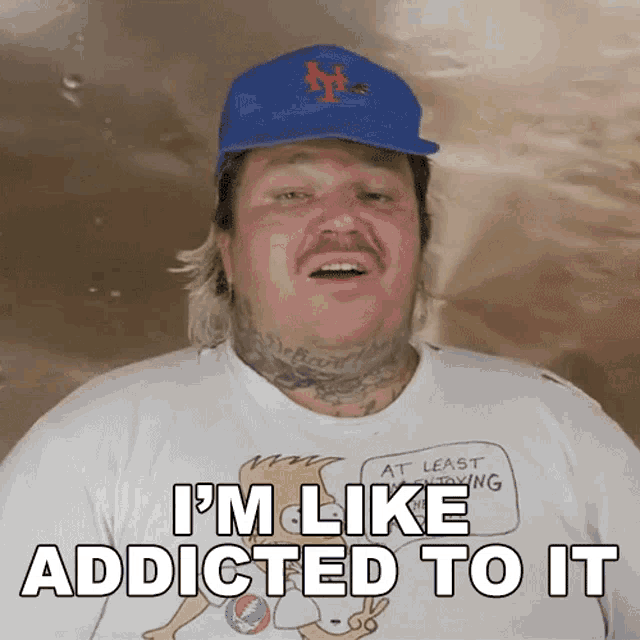 a man wearing a hat and a shirt that says i 'm like addicted to it on it