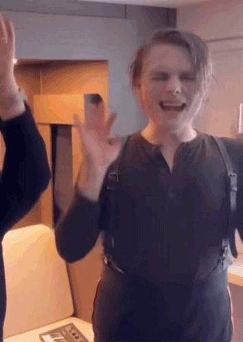 a man in a black vest is giving a high five to another man .