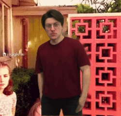 a man in a red shirt stands in front of a pink fence