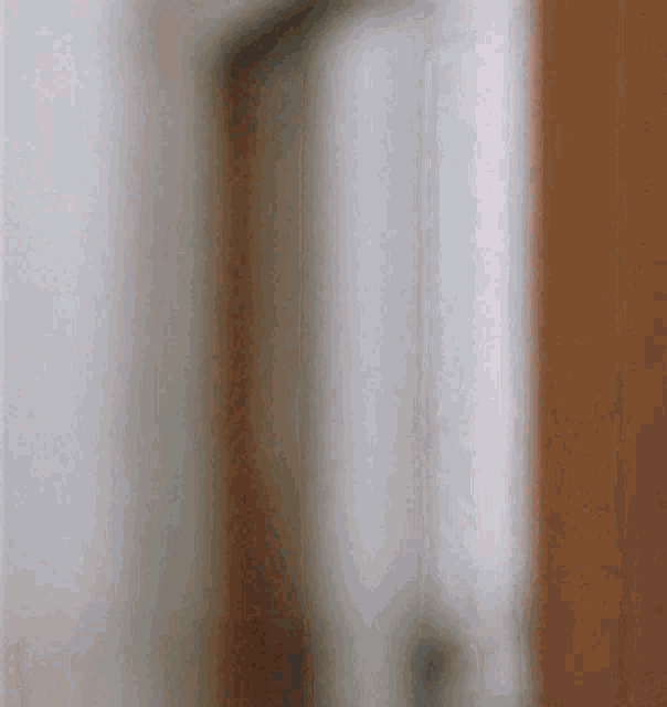 A blurred person gives a thumbs-up near a bright window.