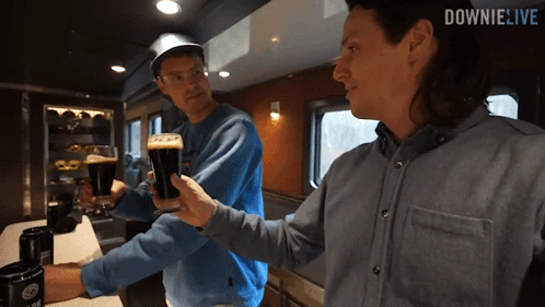 two men toasting with beer in front of a downie live logo