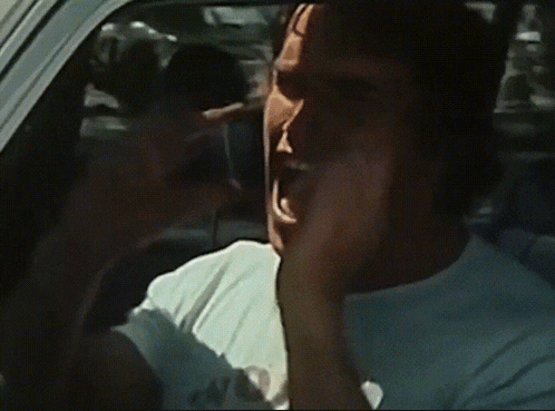 a man in a white shirt is driving a car