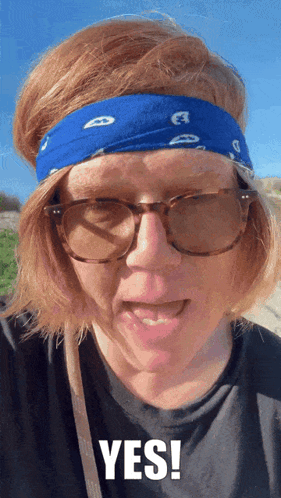a woman with red hair wearing glasses and a blue headband says yes