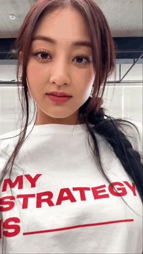 A woman in a white shirt looks sideways with red text on her clothing.