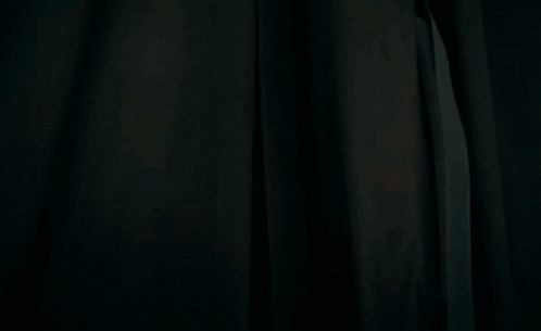 a man in a blue white and red jacket stands in a dark room