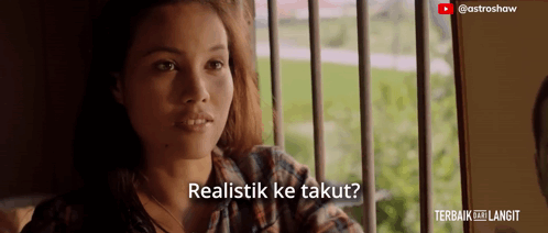 a woman sitting in front of a window with the words realistik ke takut written below her