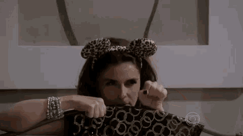 a woman is wearing a leopard print headband and holding a bag .