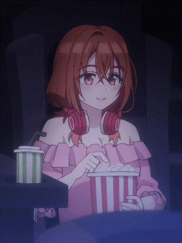 a girl wearing headphones is eating popcorn in a theater