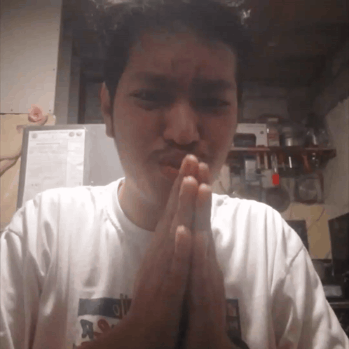 A person presses their hands together in a pleading apology gesture.