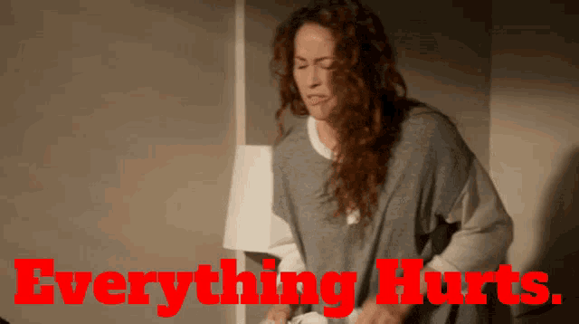 a woman is holding her stomach with the words " everything hurts " behind her
