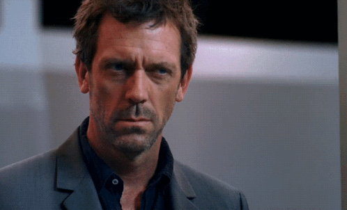 a close up of a man 's face with a black shirt and a grey suit