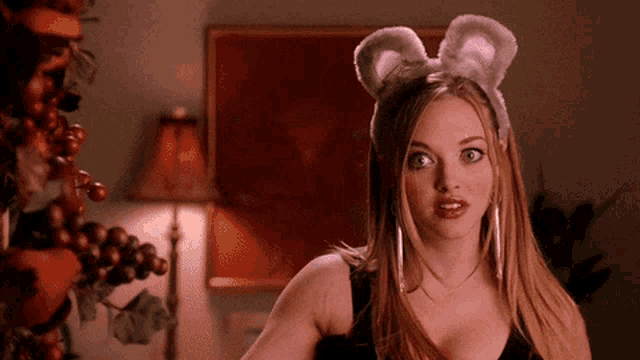 Amanda Seyfried as Karen in Mean Girls wears mouse ears and looks skeptical.