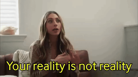 a woman is sitting on a couch with the words `` your reality is not reality '' written on the screen .