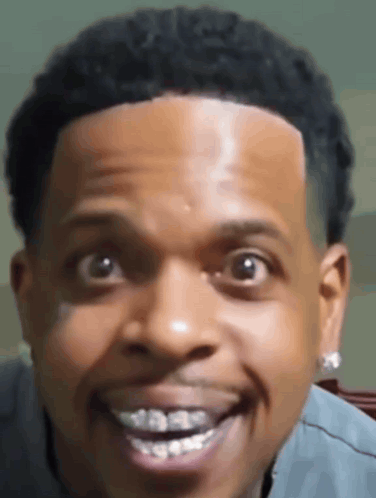 A man makes a wide-eyed toothy grin directly at the camera.