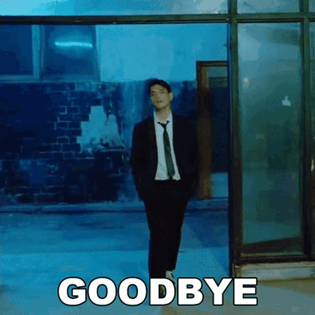 a man in a suit and tie is standing in front of a building with the words goodbye written on the floor .