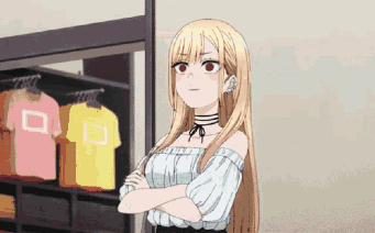 Marin Kitagawa stands with crossed arms in a shop, looking worried.