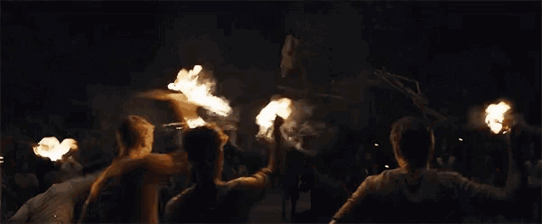 a group of people are standing in front of a burning statue .