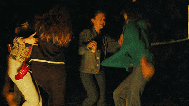a group of young women are dancing in a dark room