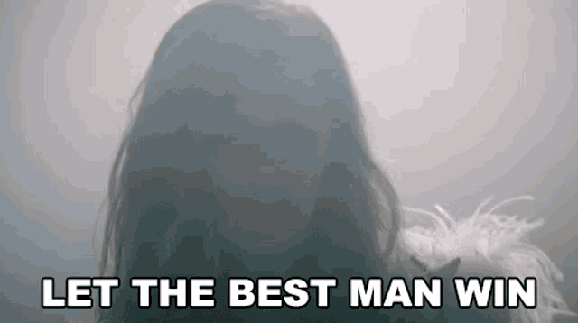 a woman in a white feather boa is saying `` let the best man win '' in a foggy room .