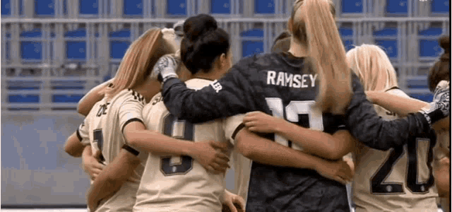 a group of female soccer players are hugging each other .