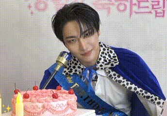 a young man is sitting in front of a cake with cherries on it .