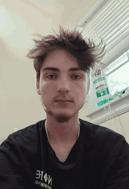 a young man wearing a black shirt with a foreign language on it looks at the camera