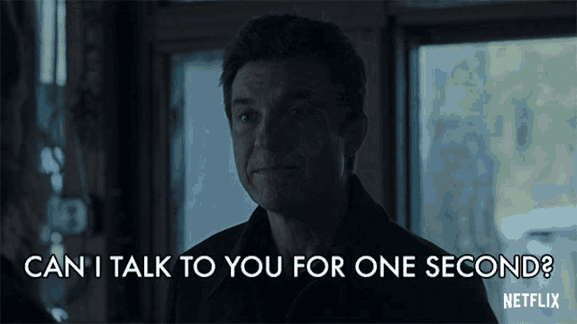 a man in a dark room with the words " can i talk to you for one second " below him