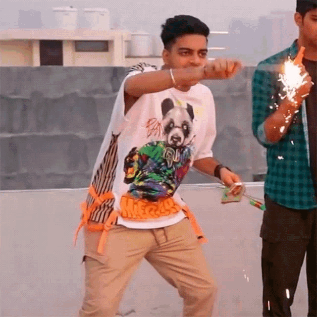 a man wearing a shirt with a panda on it holds a sparkler