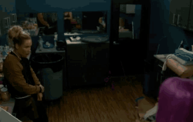 a woman with purple hair is talking to another woman in a kitchen