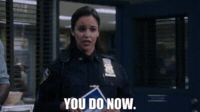 a woman in a police uniform is standing in a room and saying `` you do now . ''