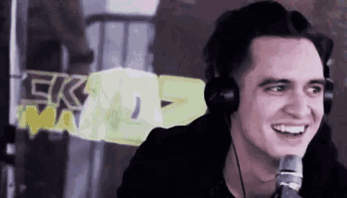 a man wearing headphones and a microphone is smiling .